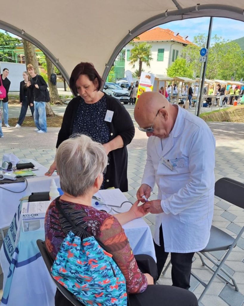 Prostovoljec drži roko druge osebe z namenom jemanj krvi za testiranje nivoja sladkorja v krvi